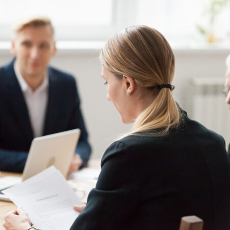 Focused serious businesswoman reading document at group meeting Serious businesswoman reading document contract at team meeting, female employee or manager holding paper at negotiations, focused company executive analyzing report during corporate group briefing